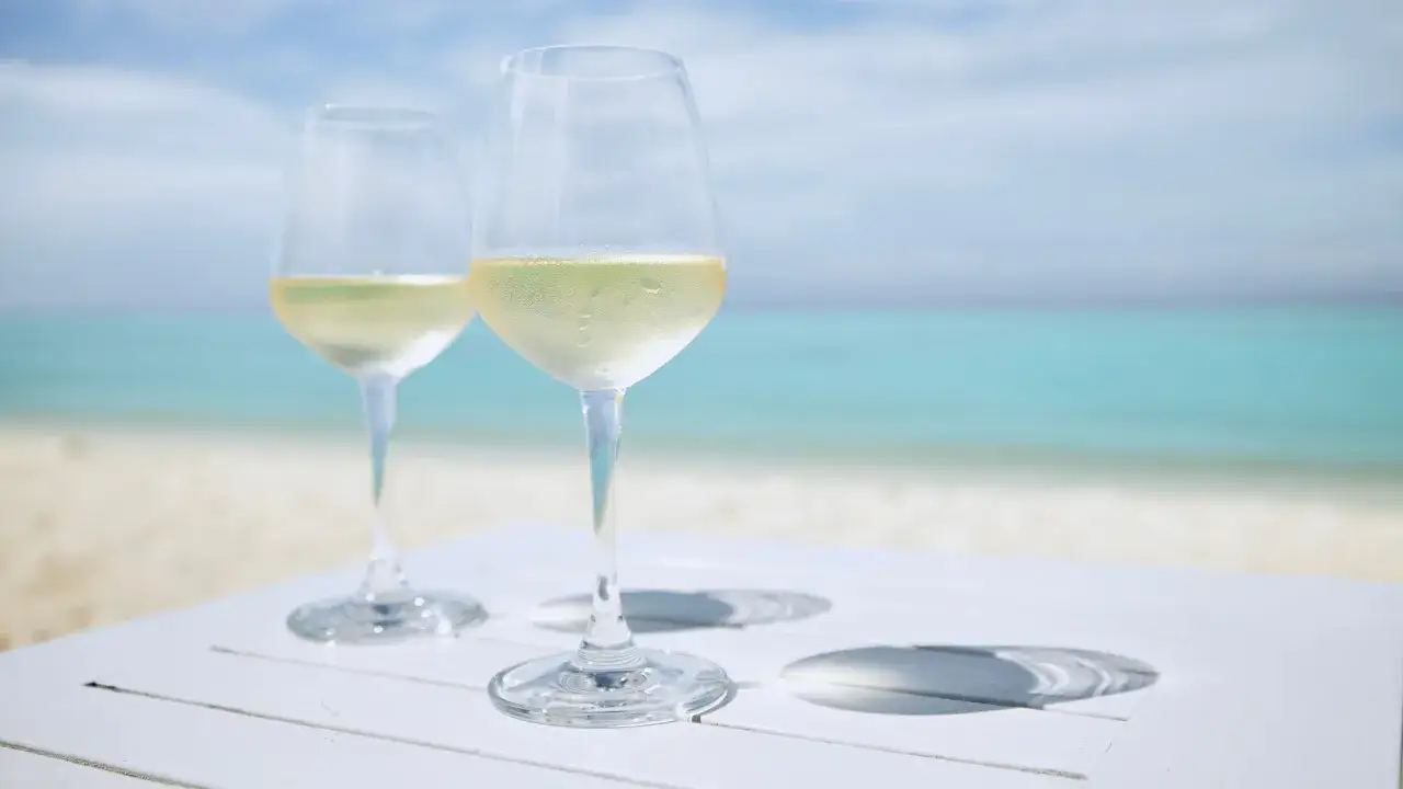 Dos copas de vino blanco frío sobre una mesa blanca en la playa. ¿El albariño es dulce o seco?
