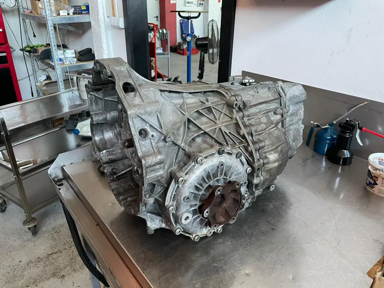 Ciężka, aluminiowa skrzynia biegów CVT leży na metalowym stole warsztatowym, gotowa do naprawy.