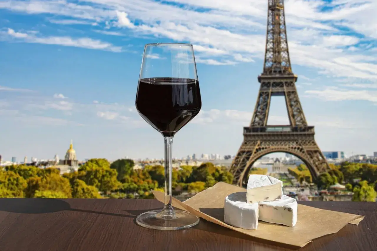 Ett glas rött vin och ost framför Eiffeltornet, som används för att visa upp Paris kultur och skönhet.