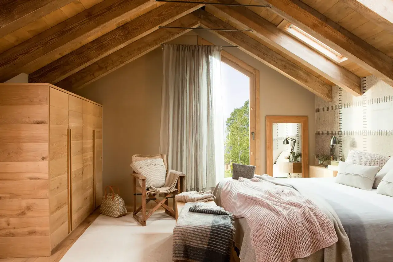 Dormitorio rústico con vigas de madera, armario empotrado, cama acogedora y sillón. Ideas para un hogar cálido.