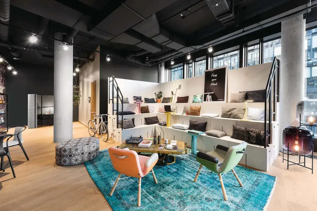 Gem&uuml;tlicher **coworking space cologne** mit Sitzstufen, Kissen, Fahrr&auml;dern und stilvollen Lampen.