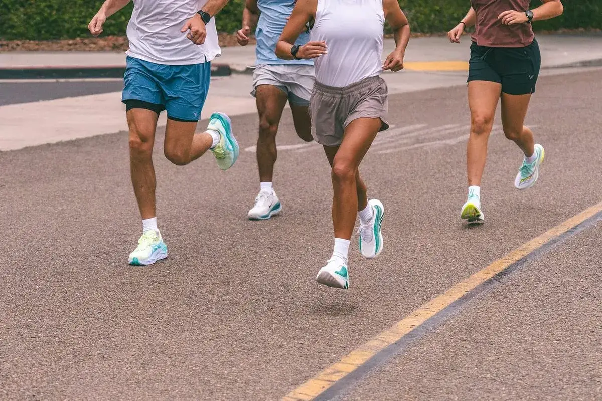 Atleti in corsa su strada, concentrati sulla preparazione mezza maratona. Scarpe da ginnastica colorate e abbigliamento sportivo.