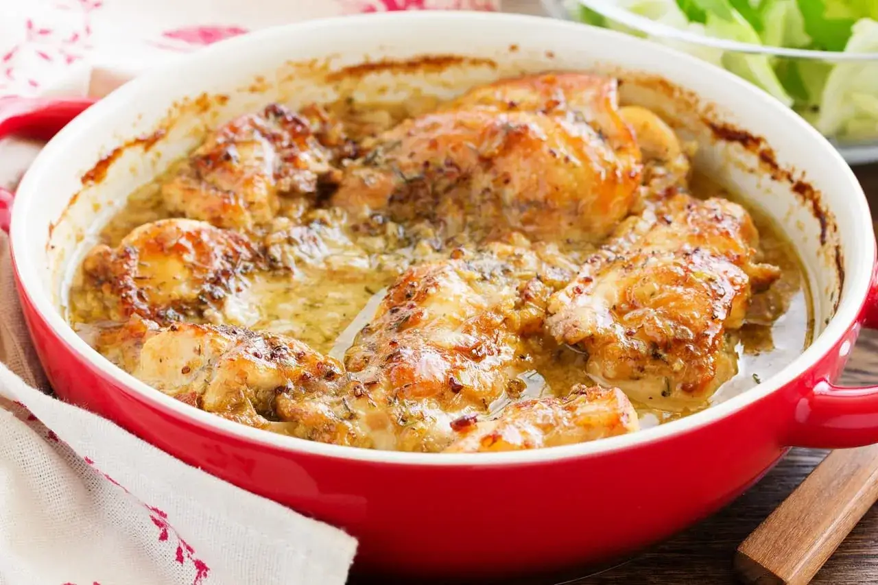 Poulet rôti dans un plat rouge, sauce crémeuse aux herbes. Un délice pour le repas du week-end.