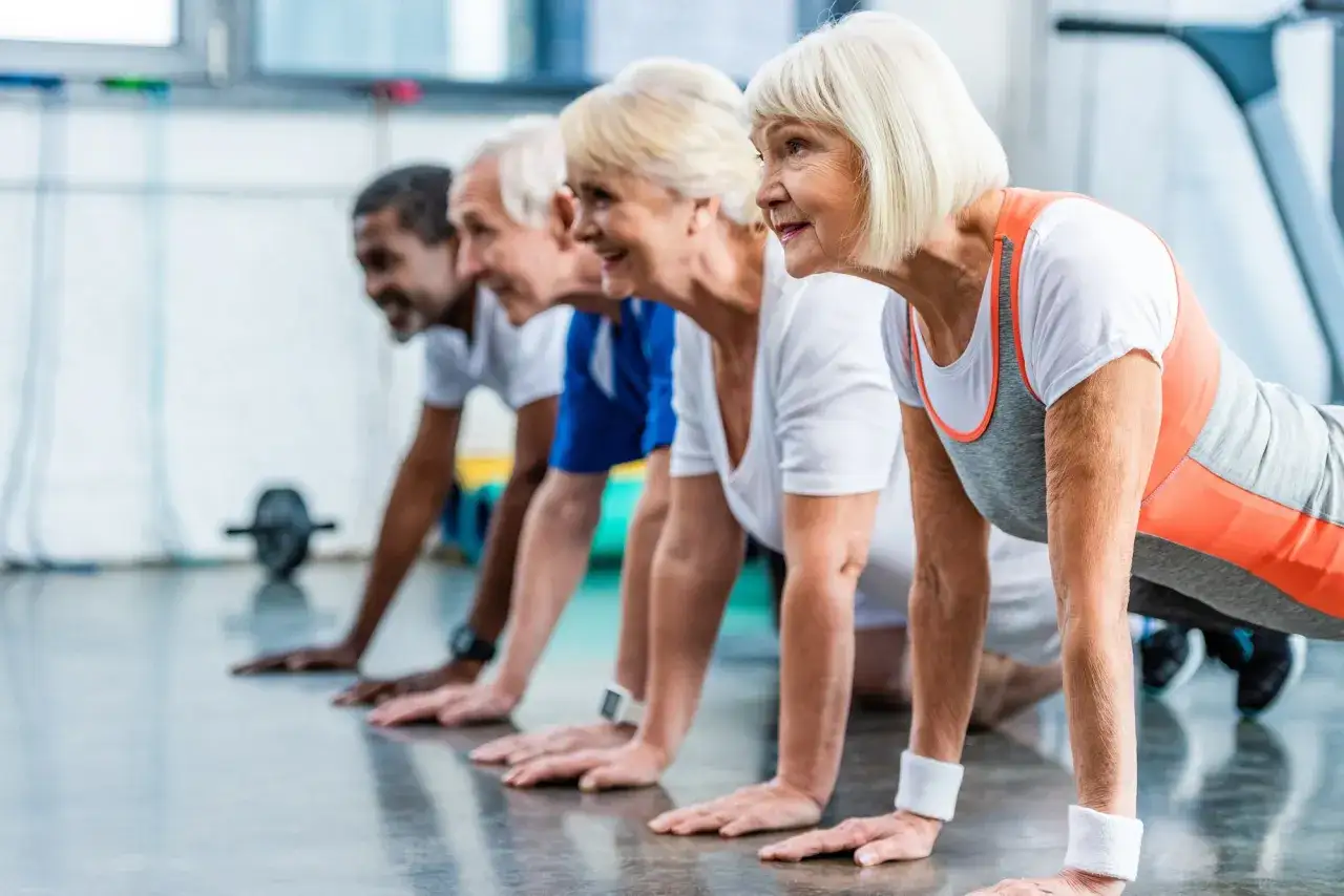 Des seniors souriants en position de planche, un bel exemple pour se motiver au sport.