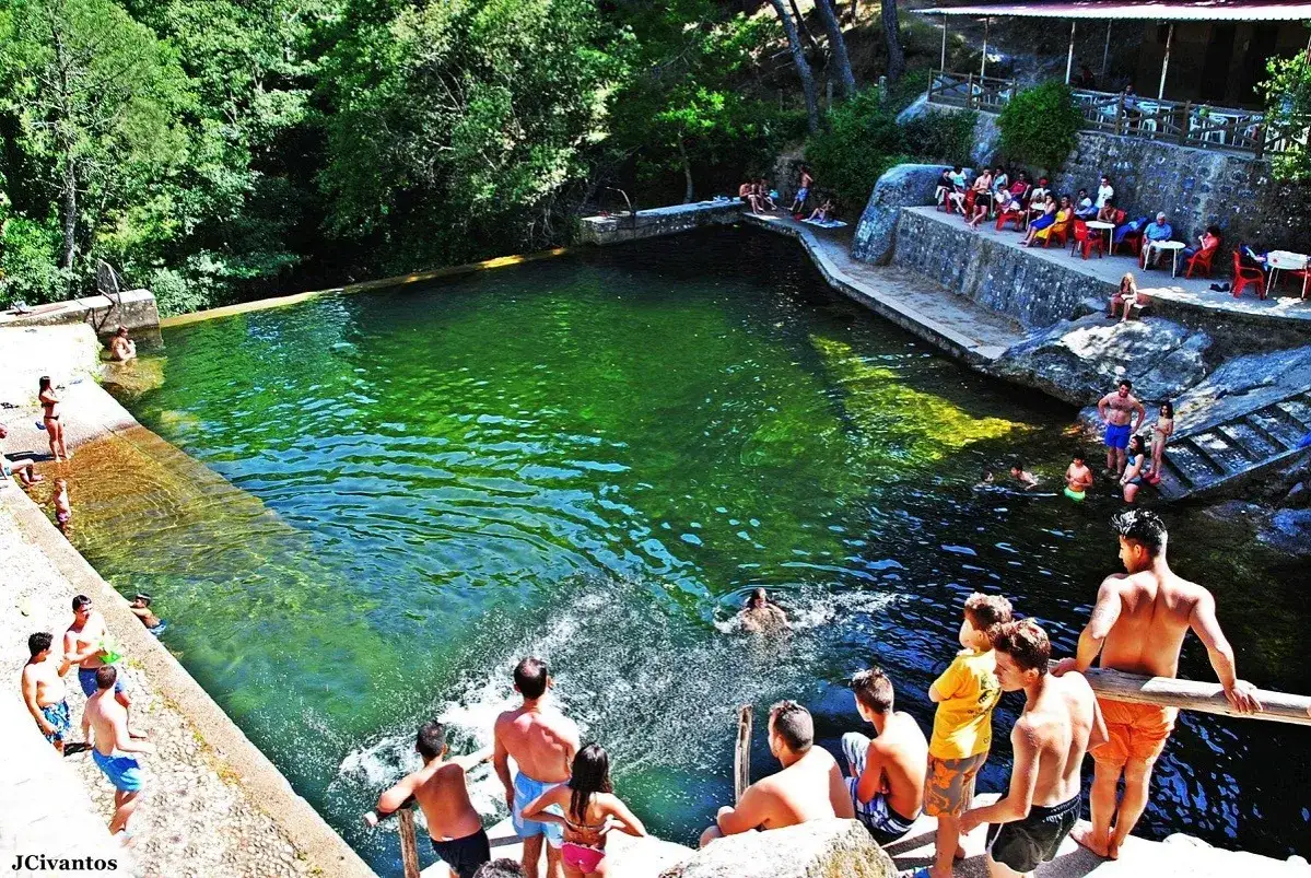 Gente disfrutando de las pozas de Madrid, un oasis verde con aguas cristalinas y rodeado de naturaleza.