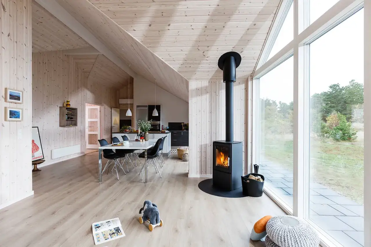 Varmt och mysigt vardagsrum med öppen spis, matplats och stora fönster. Perfekt för **hygge danska**-stunder.