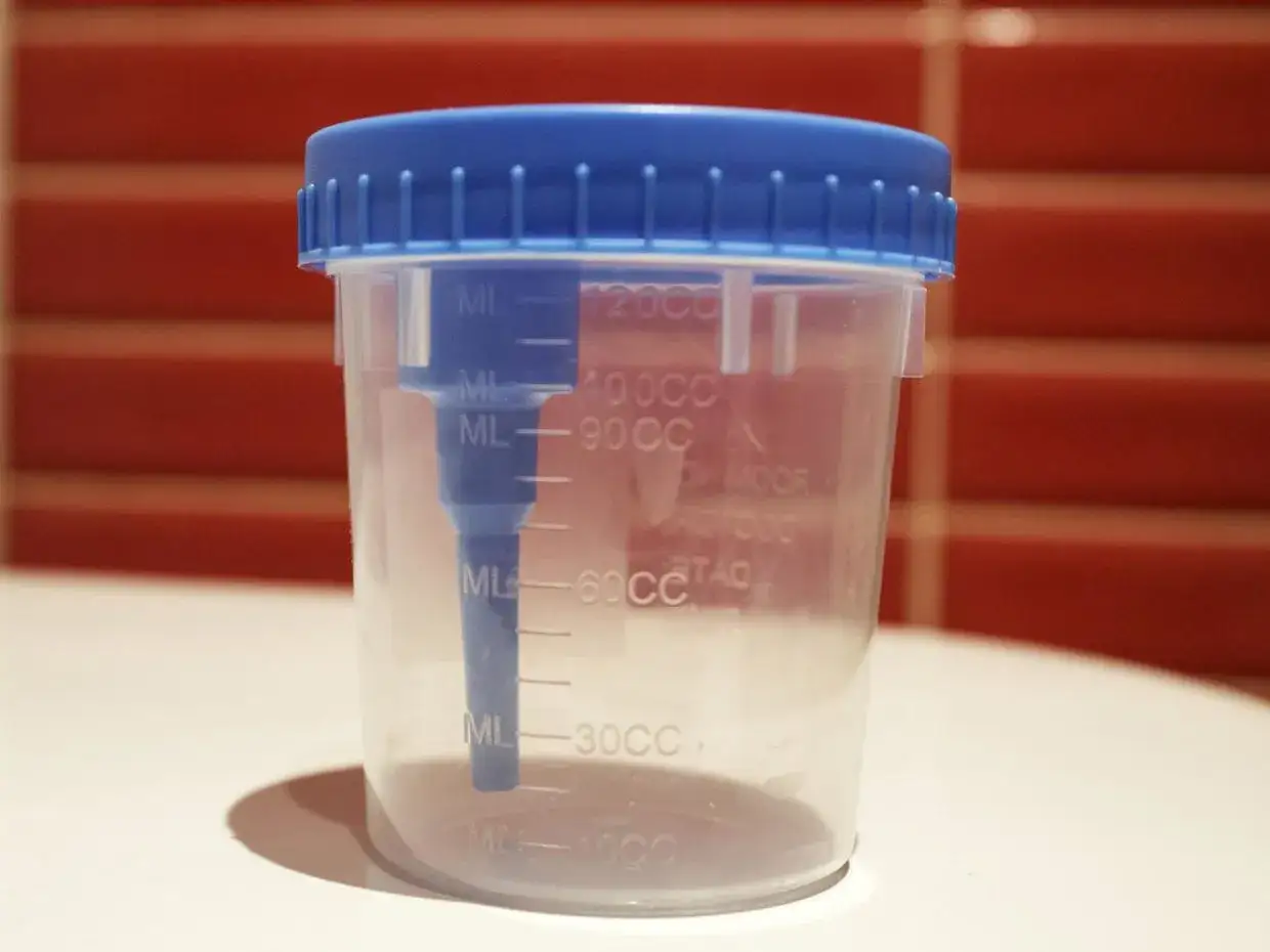 Contenitore trasparente con tappo blu per la raccolta urine neonato, graduato per misurare i volumi.
