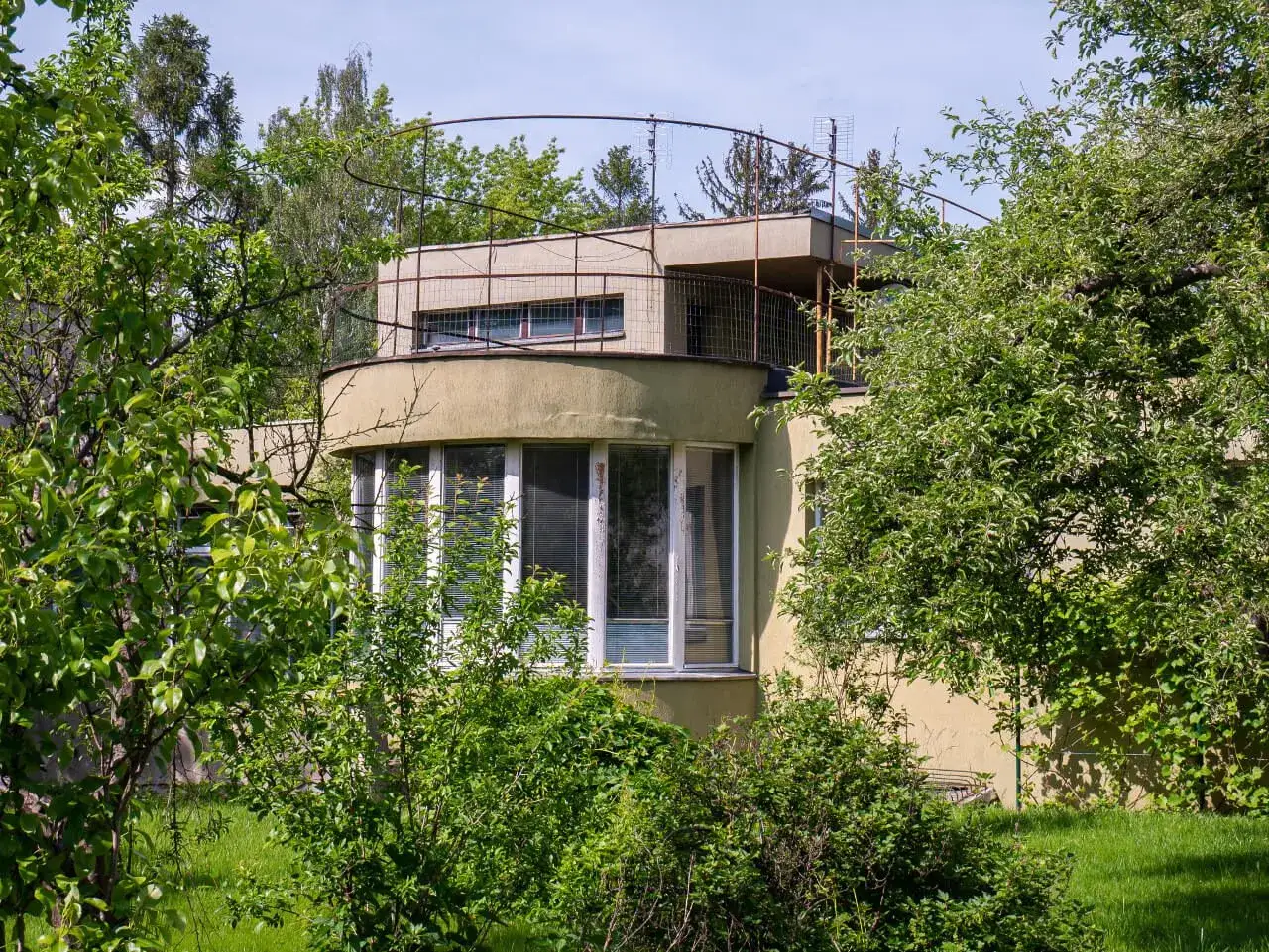 Ogród otacza modernistyczny budynek w stylu wuwa wrocław. Okrągły taras i duże okna.