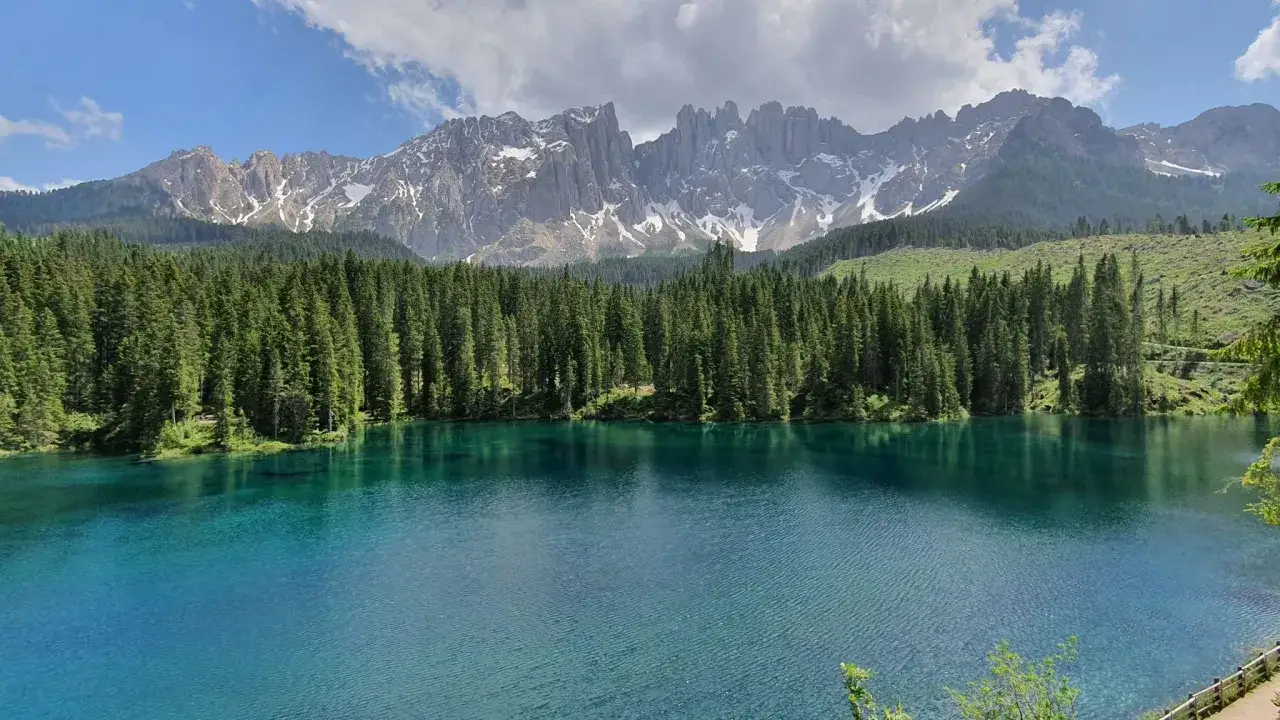Laghi alpini della Val di Fassa, con acque cristalline, foreste di conifere e maestose cime innevate sullo sfondo.