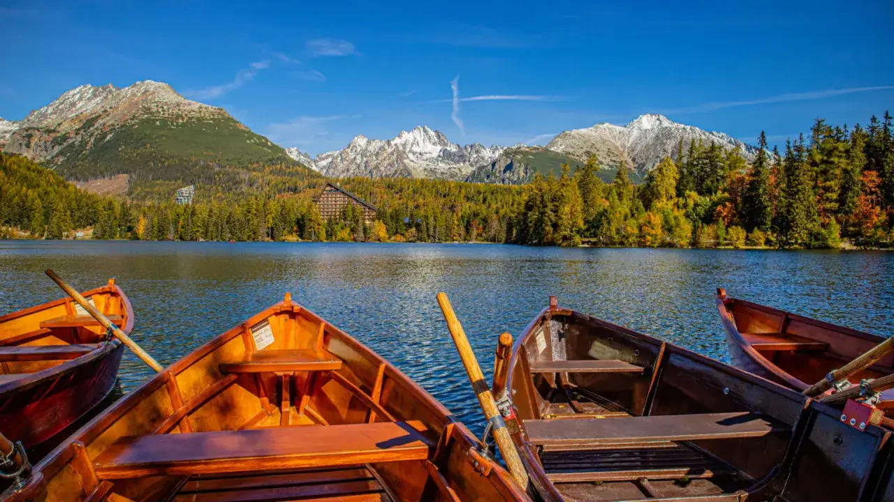 Łodzie czekają na jeziorze Strbskie Pleso, oferując wspaniałe widoki na Tatry. Słowacja atrakcje w pełnej krasie.