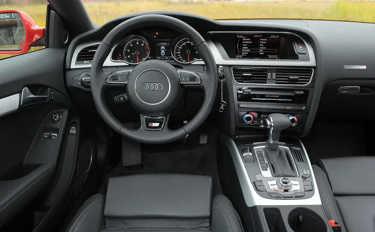 Wnętrze Audi A5 2006 z czarną skórzaną tapicerką, kierownicą S line i panelem multimedialnym.