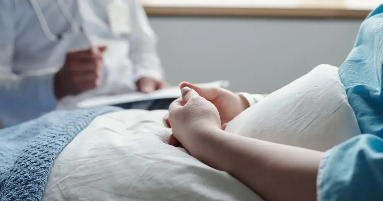 Pacjentka w szpitalu, z dłońmi złożonymi na brzuchu, słucha lekarza. Czy leczenie biologiczne to chemia?