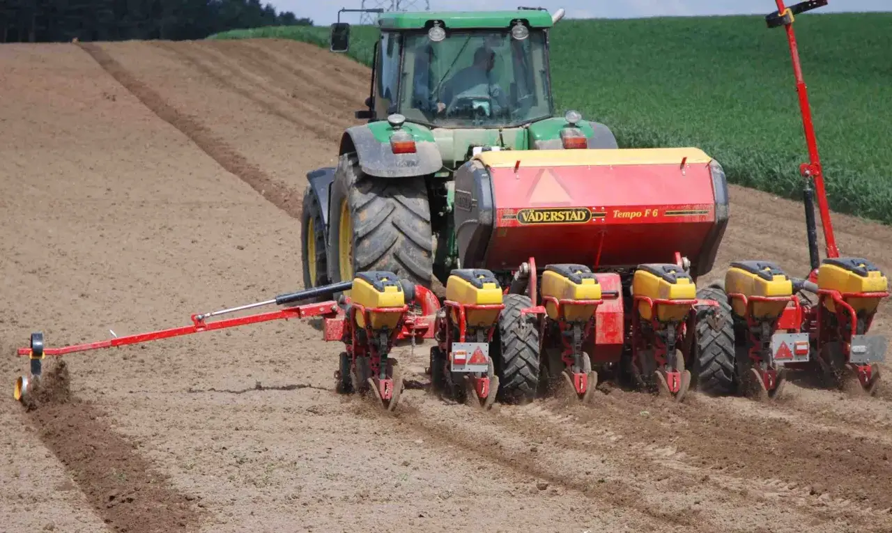 Traktor z siewnikiem precyzyjnym sadzi kukurydzę w Polsce. Nowoczesna technologia zapewnia równomierne rozmieszczenie nasion.