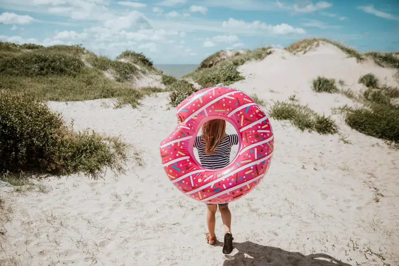 Barn med badring som en munk p&aring; en sandig strand i Halland.