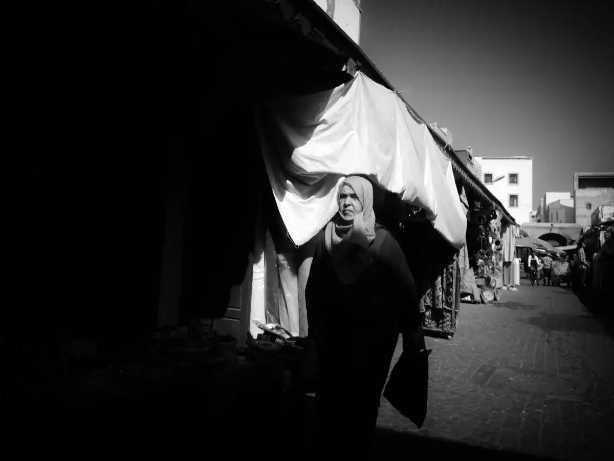 Donna velata in un mercato, un esempio di street photography. Ombre e luci creano un'atmosfera intensa.