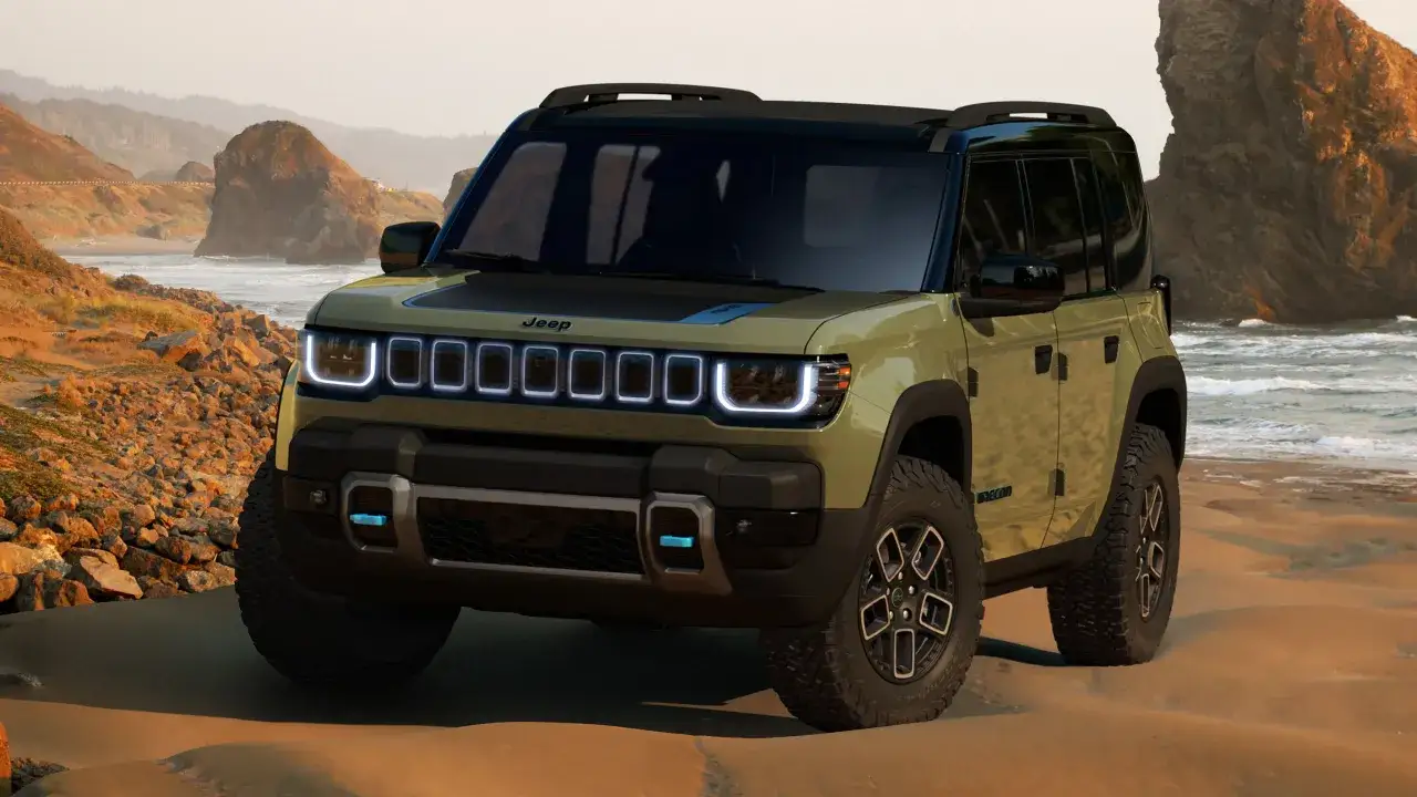 Nowy Jeep mhero na piaszczystej plaży, z falami w tle.