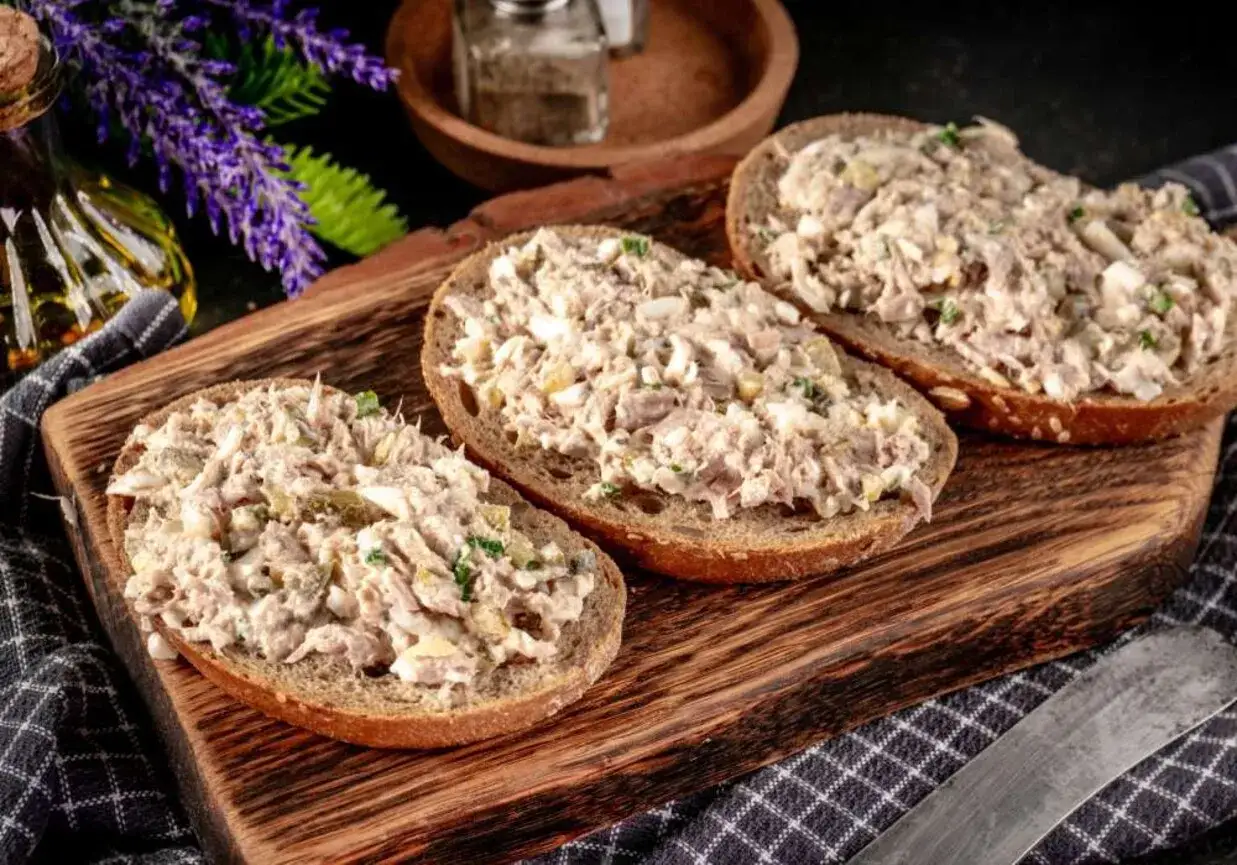 Trzy kromki ciemnego pieczywa obficie posmarowane pastą z tuńczyka, jajka i ziół. Idealna przekąska na szybki lunch.