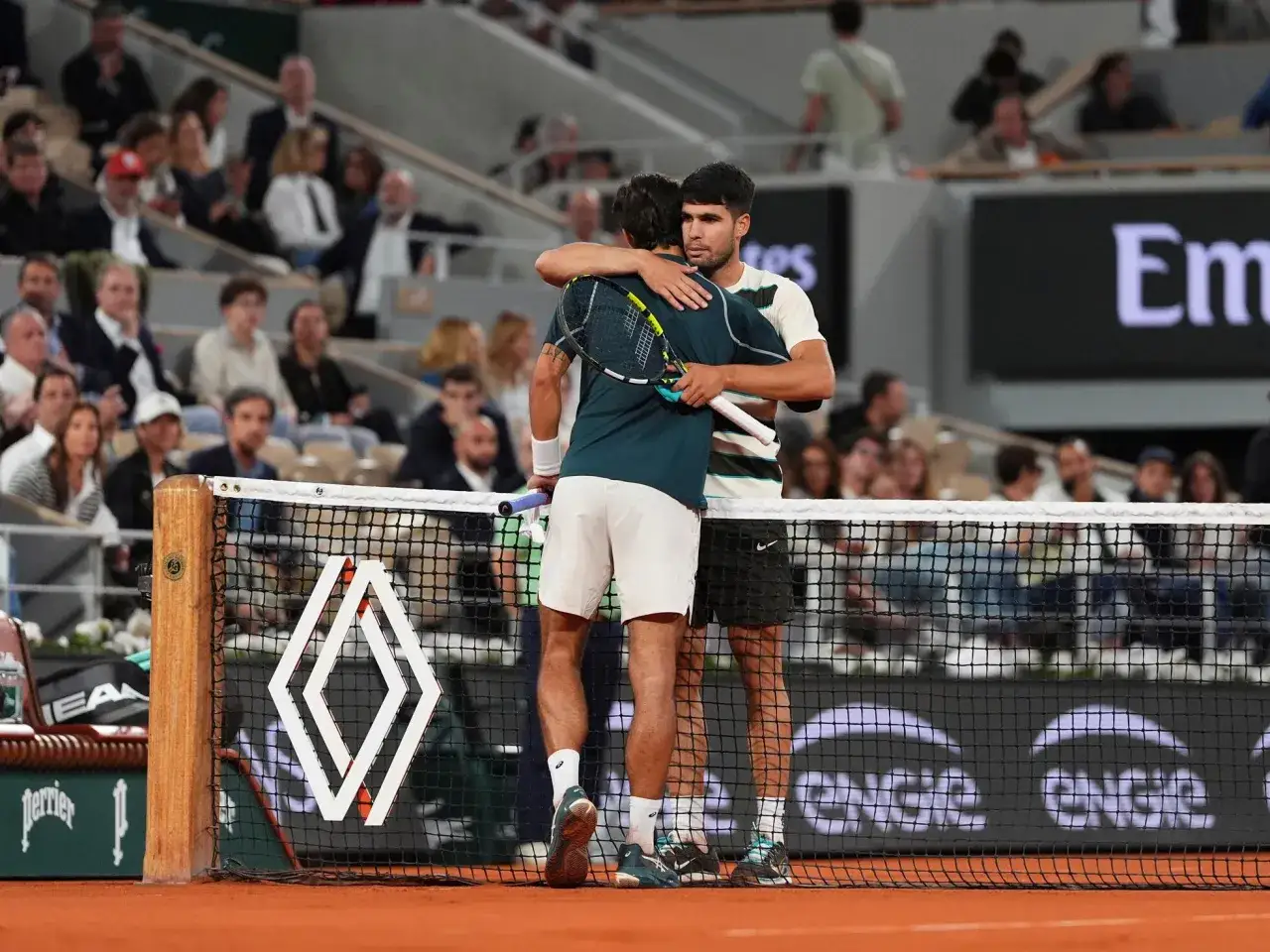Carlos Alcaraz y Musetti se abrazan en la cancha de tenis, mostrando deportividad tras un partido.