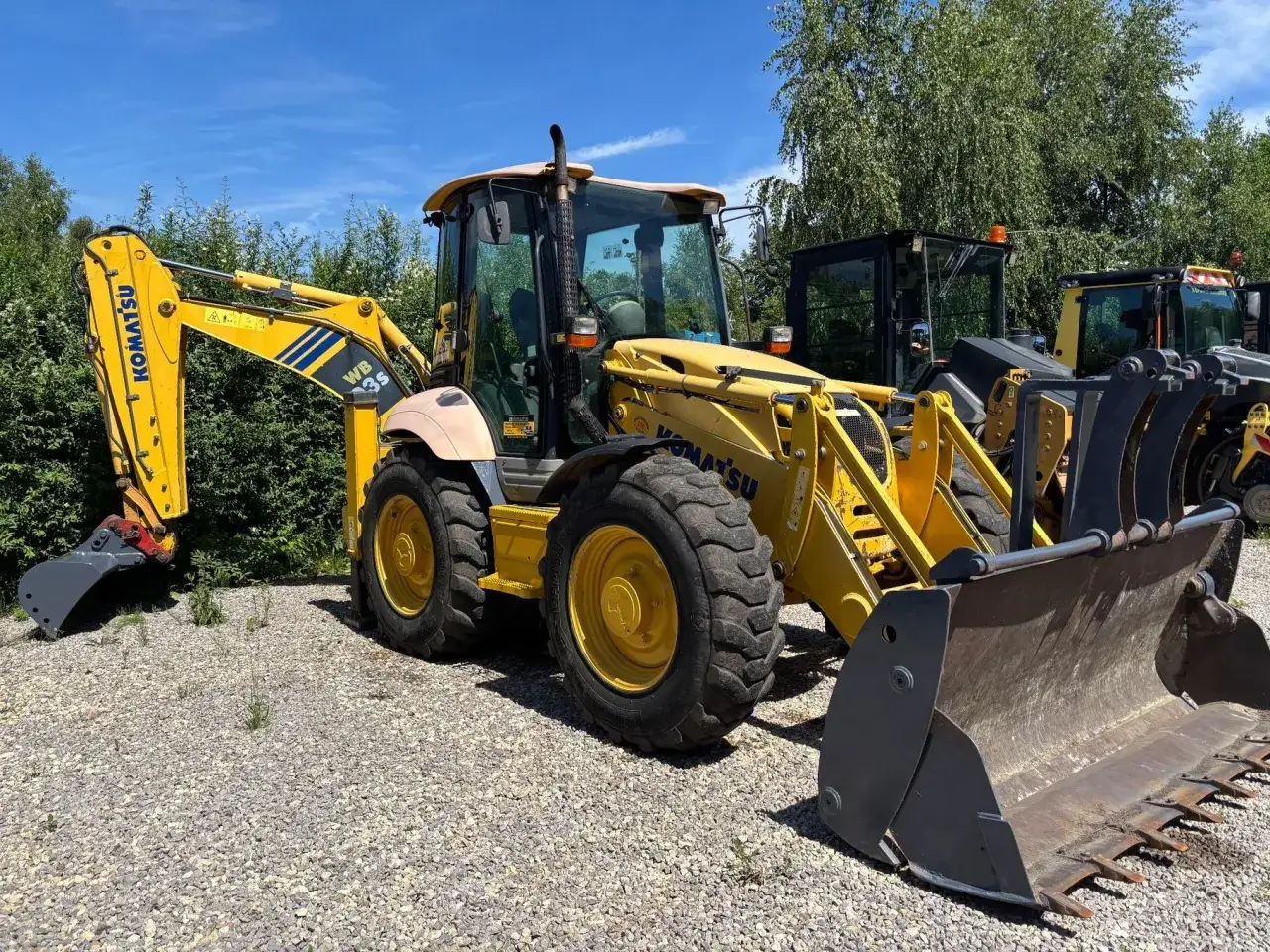 Żółta koparko-ładowarka Komatsu WB93S, jedna z wielu maszyn budowlanych, gotowa do pracy.