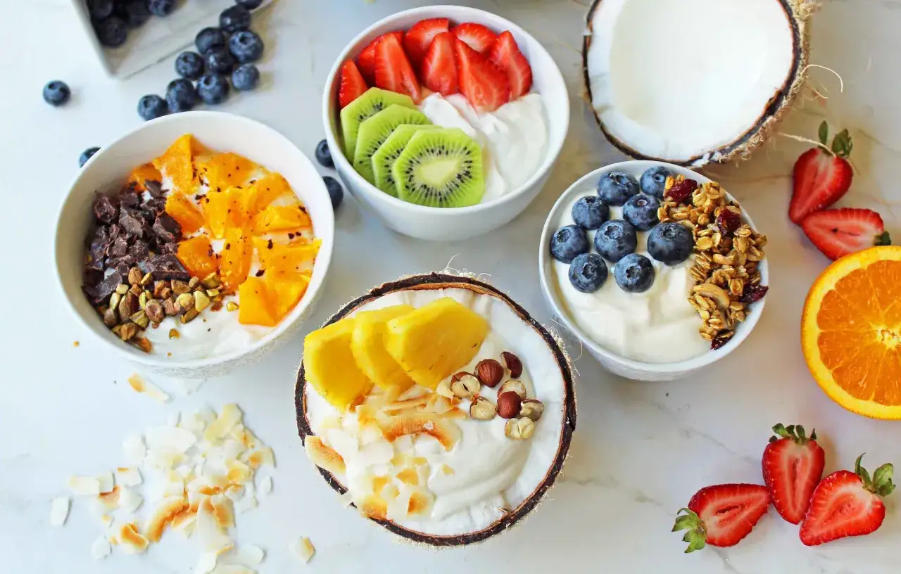 Sch&uuml;ssel mit griechischem Joghurt, garniert mit Beeren, Kiwi, Orangen, N&uuml;ssen und Kokosflocken. Griechischer Joghurt gesund und lecker.