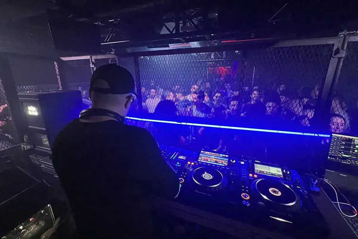 DJ set al Moog di Barcellona, con la folla che balla sotto le luci blu.