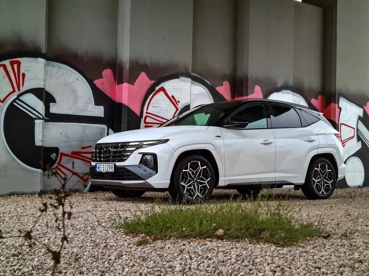 Biały Hyundai Tucson 1.6 benzyna 150KM zaparkowany przy graffiti. Zastanawiasz się, ile pali?