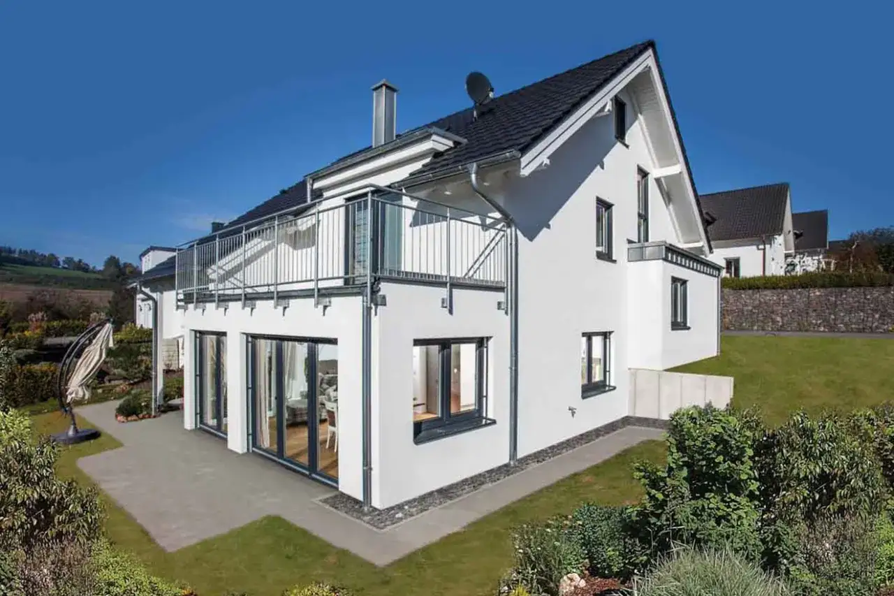 Moderne split-level haus ideen: weißes Haus mit Balkon, großen Fenstern und Terrasse, umgeben von Grün.