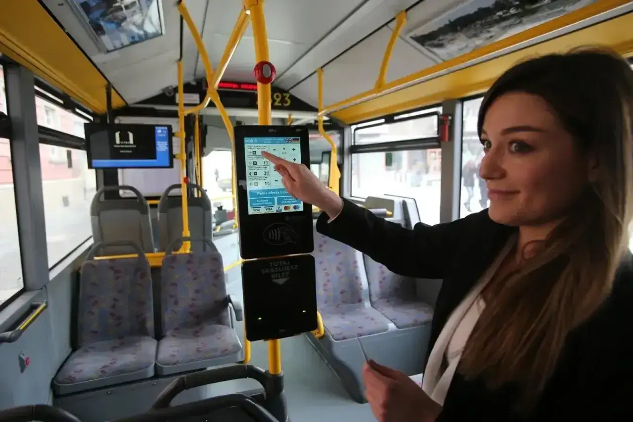 Kobieta kupuje mpk wrocław bilety ulgowe na ekranie dotykowym w autobusie.