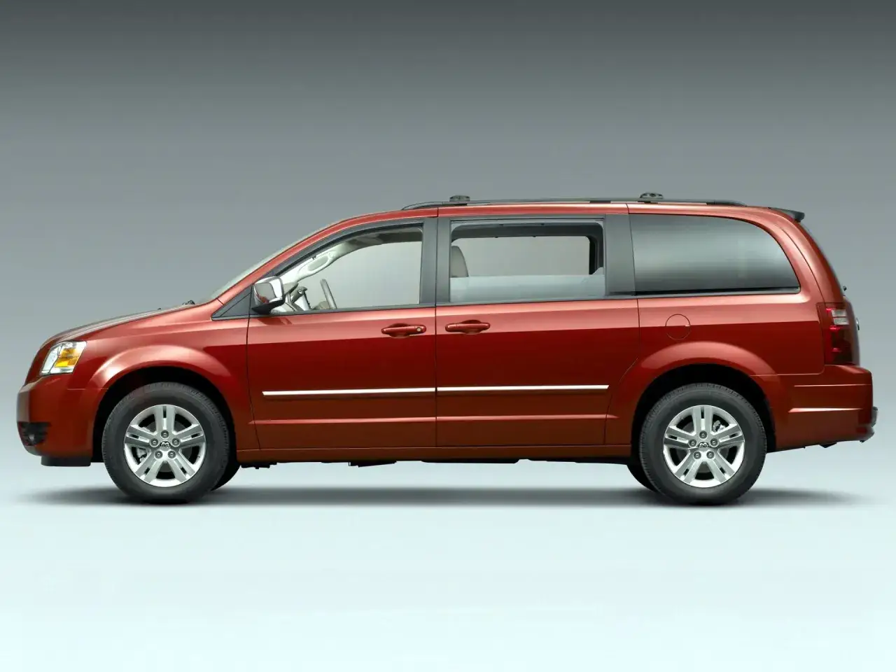 Czerwony grand caravan stoi na szarym tle.