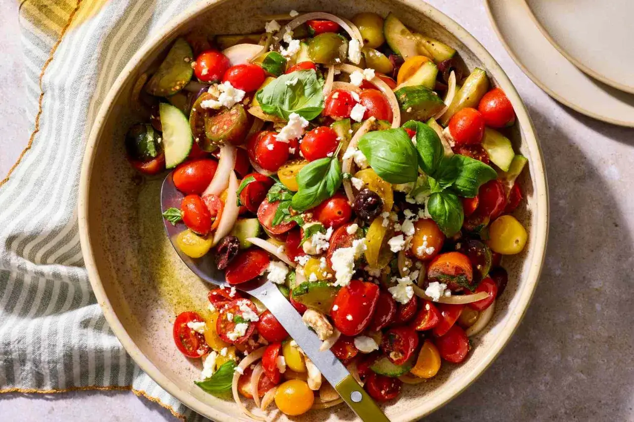 Frischer tomatensalat mit feta, Gurken, Zwiebeln und Basilikum in einer Sch&uuml;ssel.