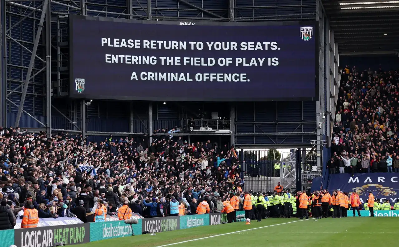 Trybuna stadionu angielskiego klubu piłkarskiego West Bromwich Albion. Na telebimie wyświetlono komunikat: