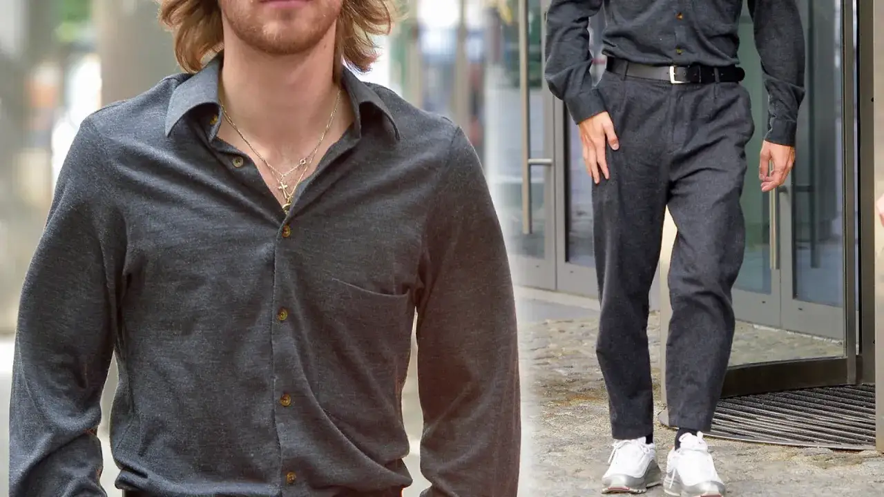 Maciej Musiał wzrost. Aktor w szarym dresie i białych sneakersach, z naszyjnikami na szyi.