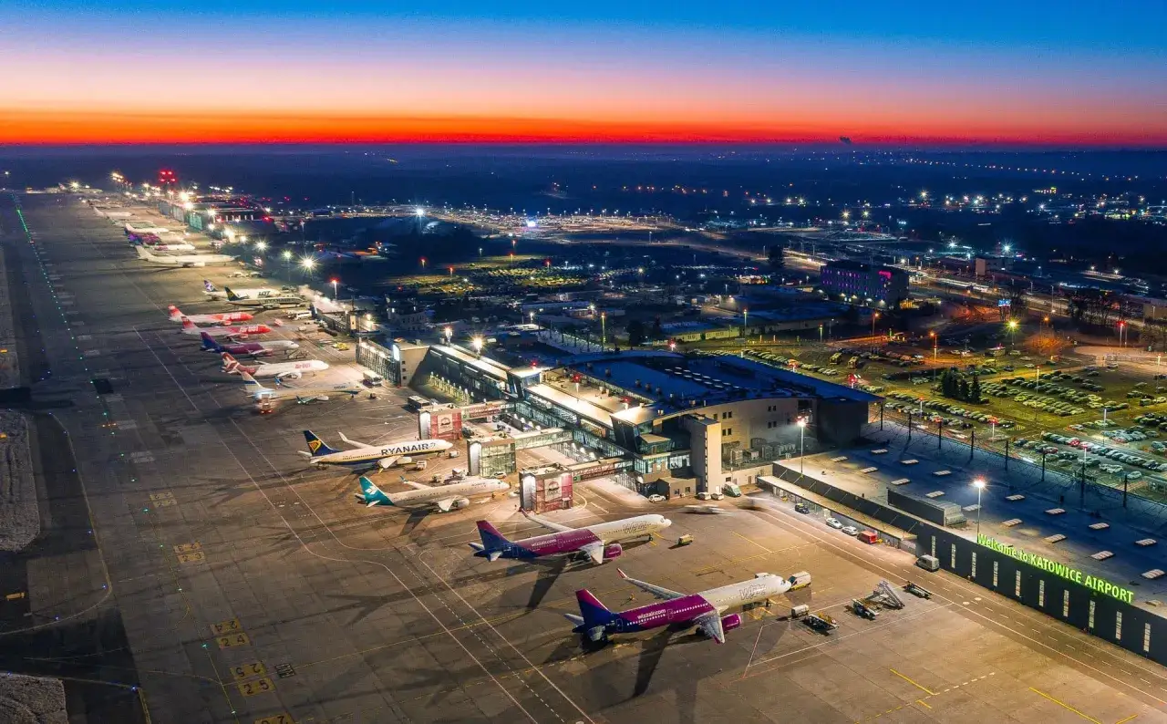 Lotnisko Katowice nocą, samoloty czekają na pasażerów. Zastanawiasz się, ile trwa lot z Katowic do Hurghady?