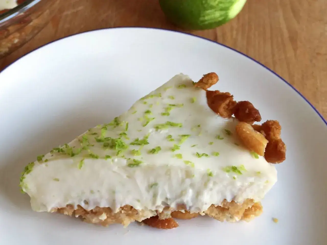 Rebanada de key lime pie cremosa, con ralladura de lima y trozos de galleta en la base.