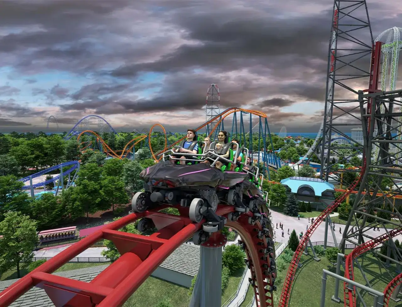 Wagonik rollercoastera z pasażerami pędzi po czerwonym torze, w tle inne kolejki i park rozrywki.
