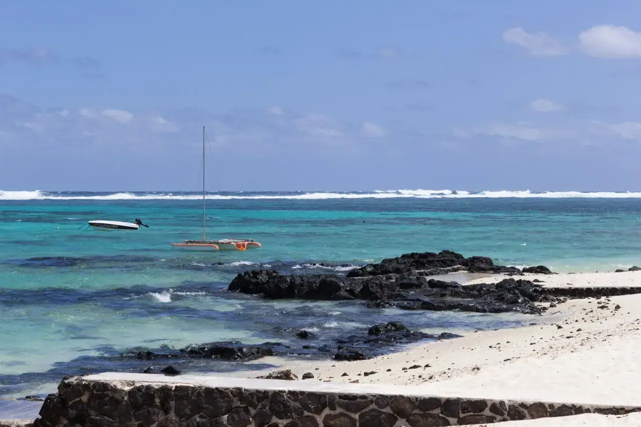 Türkisblaues Meer mit Wellen, ein Katamaran und ein Motorboot. Die Regenzeit auf Mauritius bringt diese dramatische Kulisse.