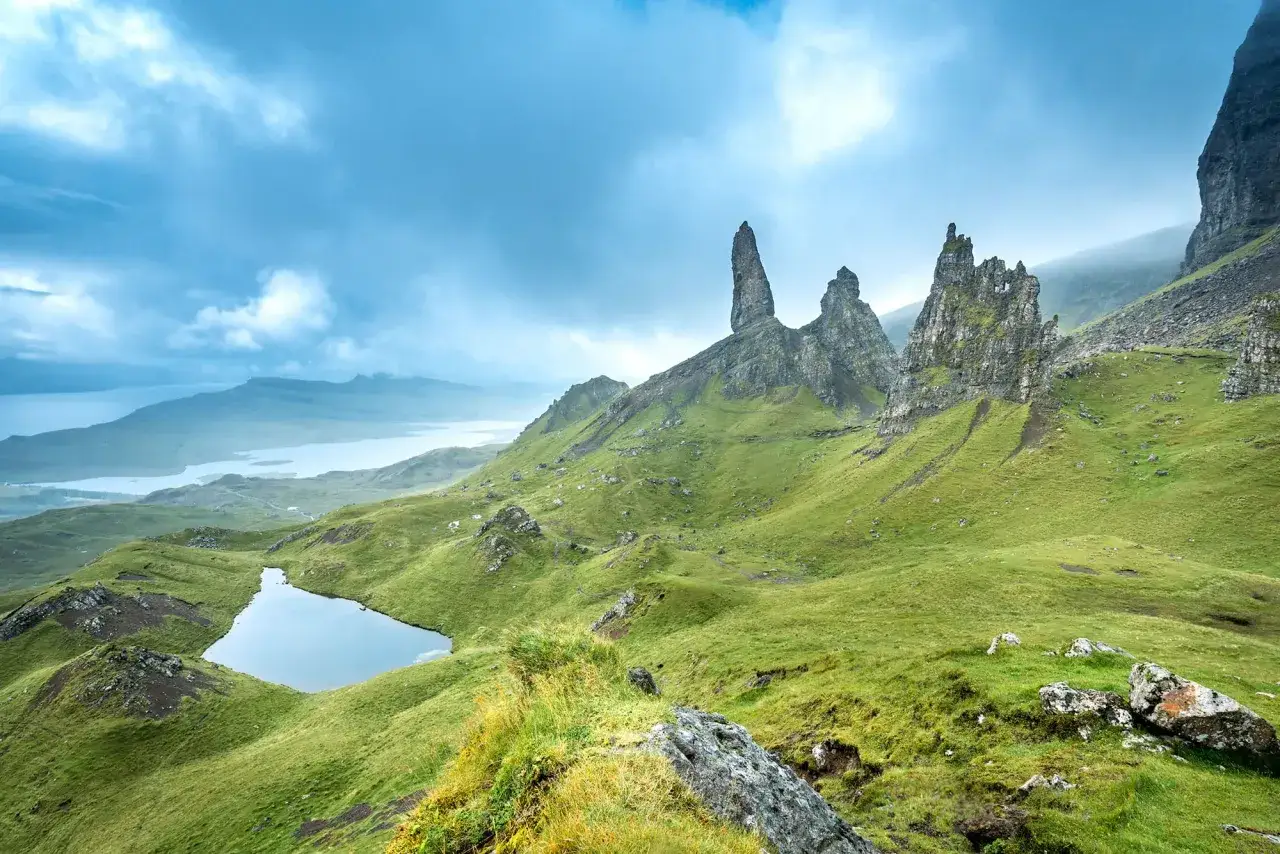 Majestatyczne skały i zielone wzgórza na wyspie Skye, idealne na podróż do Szkocji. Jezioro odbija niebo.