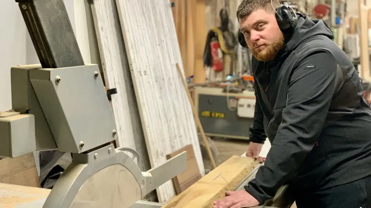 Un artisan qui travaille le bois, concentr&eacute;, utilise une scie circulaire dans son atelier.