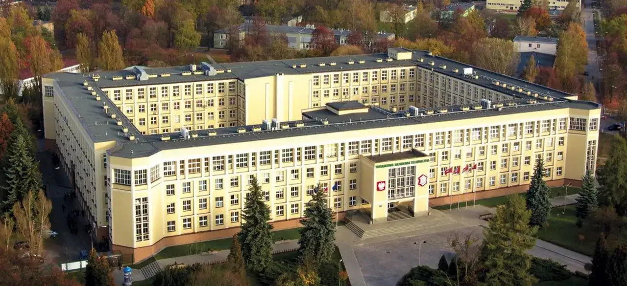 Wojskowa Akademia Techniczna im. Jarosława Dąbrowskiego, z lotu ptaka, jesienią. Budynek w kształcie litery U, otoczony drzewami.
