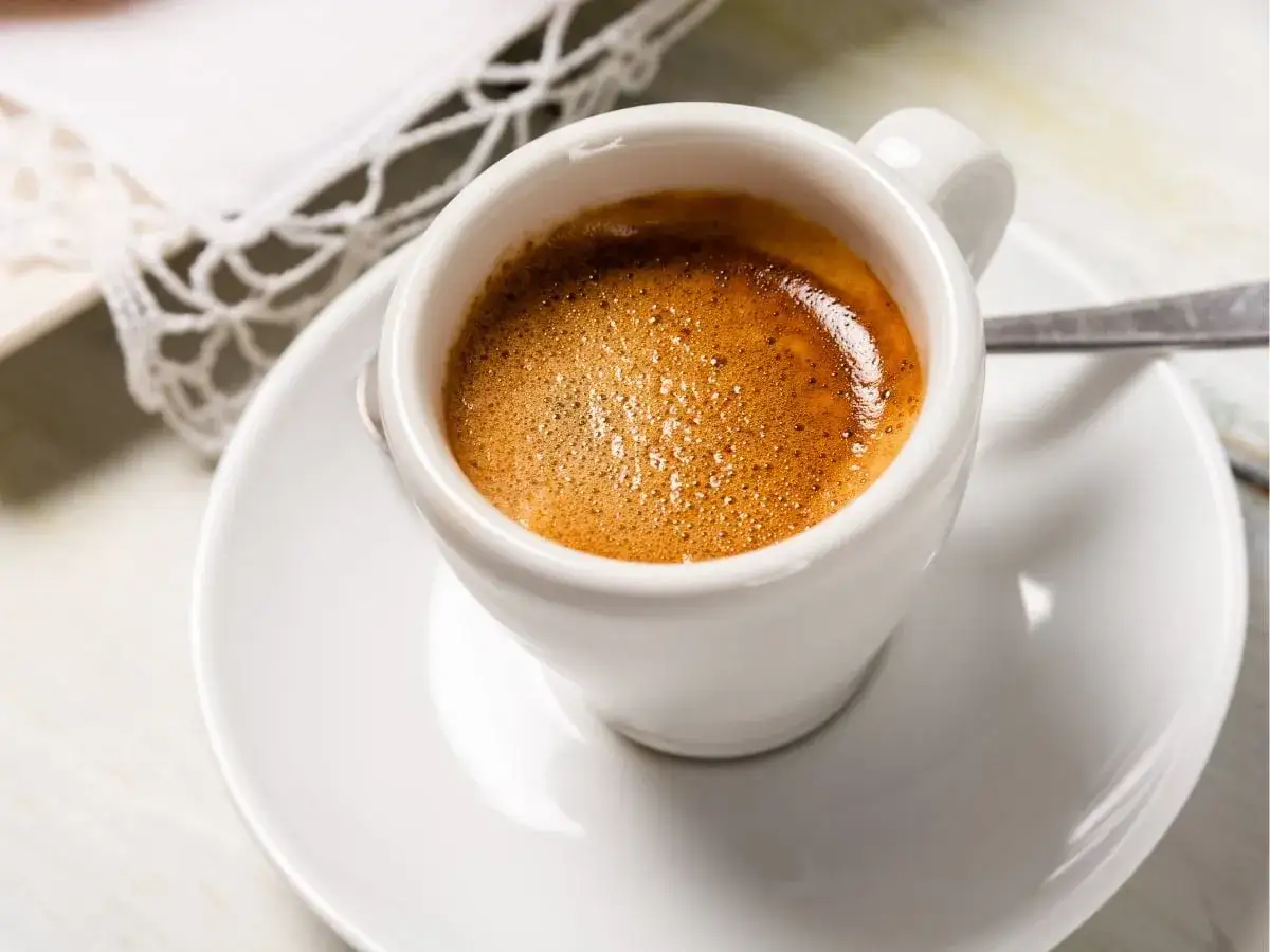 Un invitante **caffè liscio** con una crema dorata, servito in una tazzina bianca su un piattino. Un momento di puro piacere.