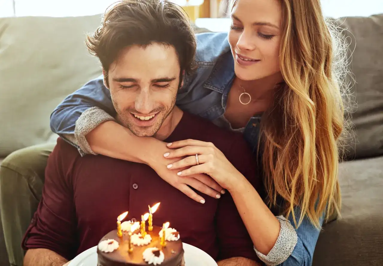 Pareja celebrando un cumpleaños con pastel y velas. Un momento perfecto para dedicarle frases bonitas para felicitar cumpleaños a tu pareja.