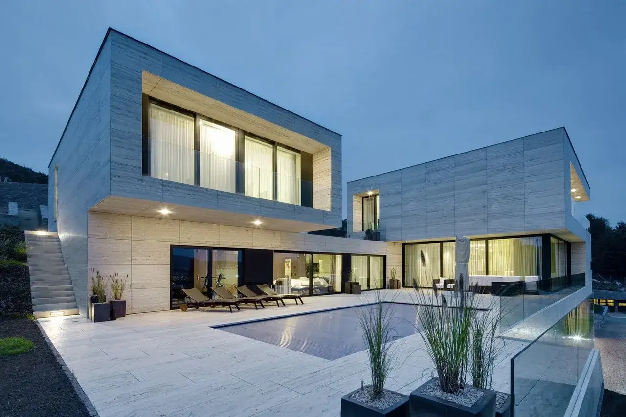 Une maison container moderne avec piscine et terrasse en pierre. L'architecture audacieuse et les grandes baies vitrées créent un espace de vie lumineux.