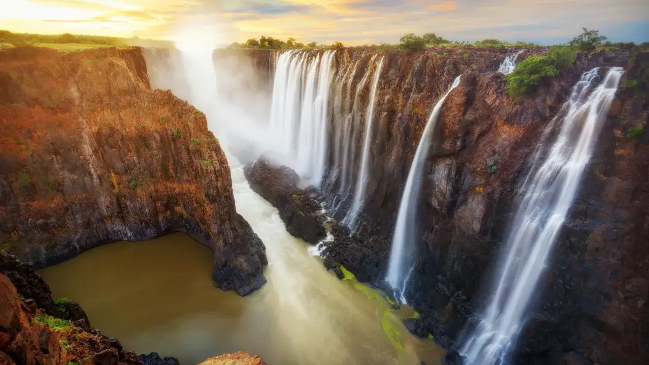 Spektakularne wodospady w Zimbabwe, jedne z największych atrakcji kraju, tworzą mglistą zasłonę na tle zachodzącego słońca.