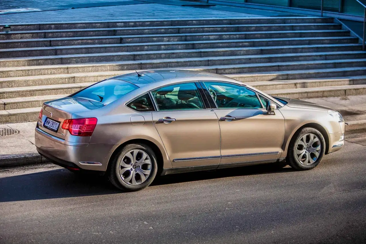 Złoty Citroen C5 X7 zaparkowany przy schodach.