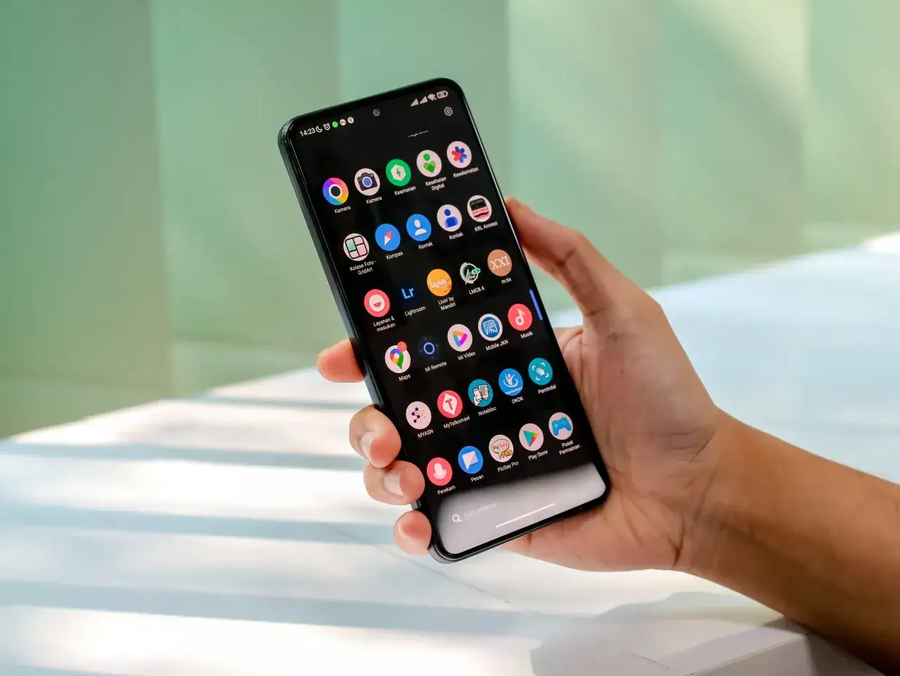 Dłoń trzyma smartfon z ikonami aplikacji, w tym aparatem, mapami i sklepem Play. System operacyjny to Tizen.