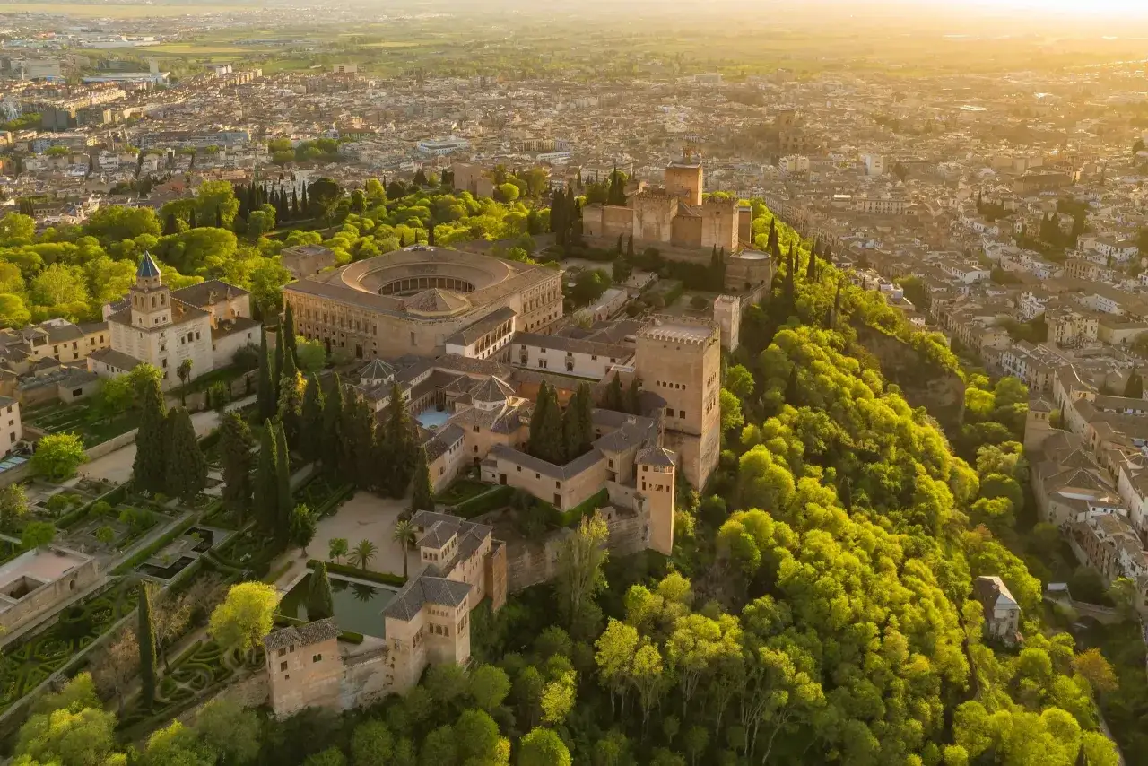 Widok z lotu ptaka na Alhambrę w Granadzie, otoczoną zielenią i miastem. Marzysz o zwiedzaniu? Sprawdź alhambra bilety!