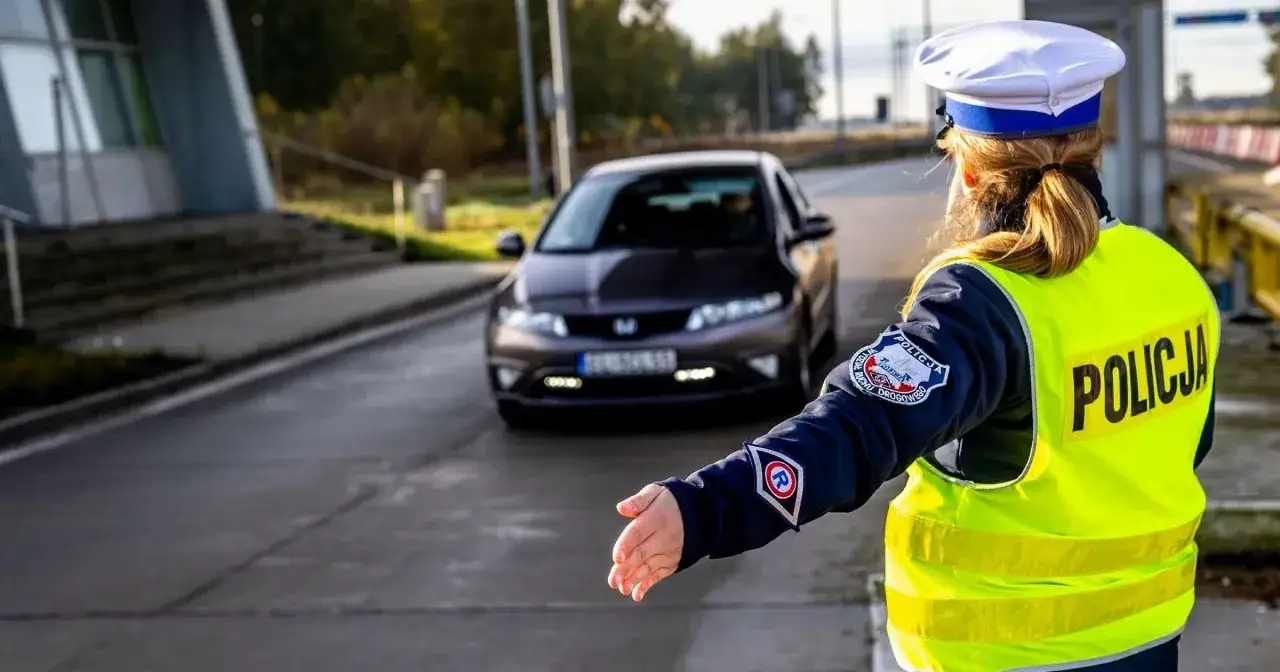 Policjantka zatrzymuje samochód, który prawdopodobnie otrzyma mandat za brak świateł.