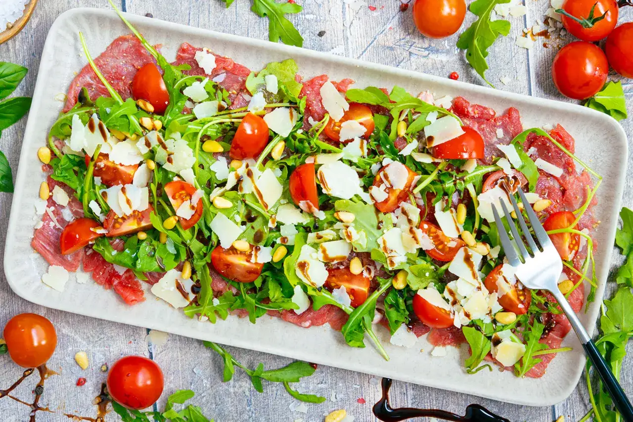 Rinder Carpaccio mit Rucola, Kirschtomaten, Pinienkernen und Parmesan. Ein köstlicher Genuss!