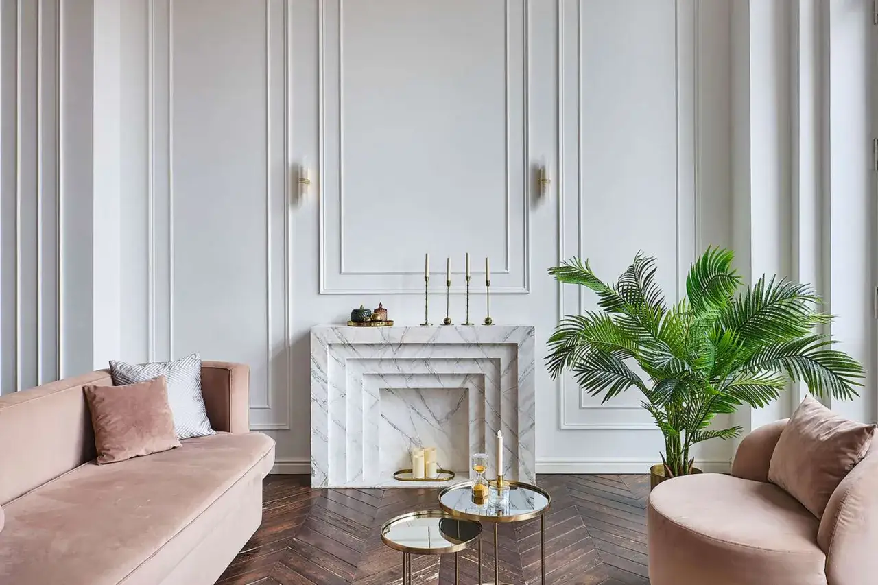 A luxurious living room designed by top interior designers, featuring a plush pink sofa, marble fireplace, and a large palm plant.