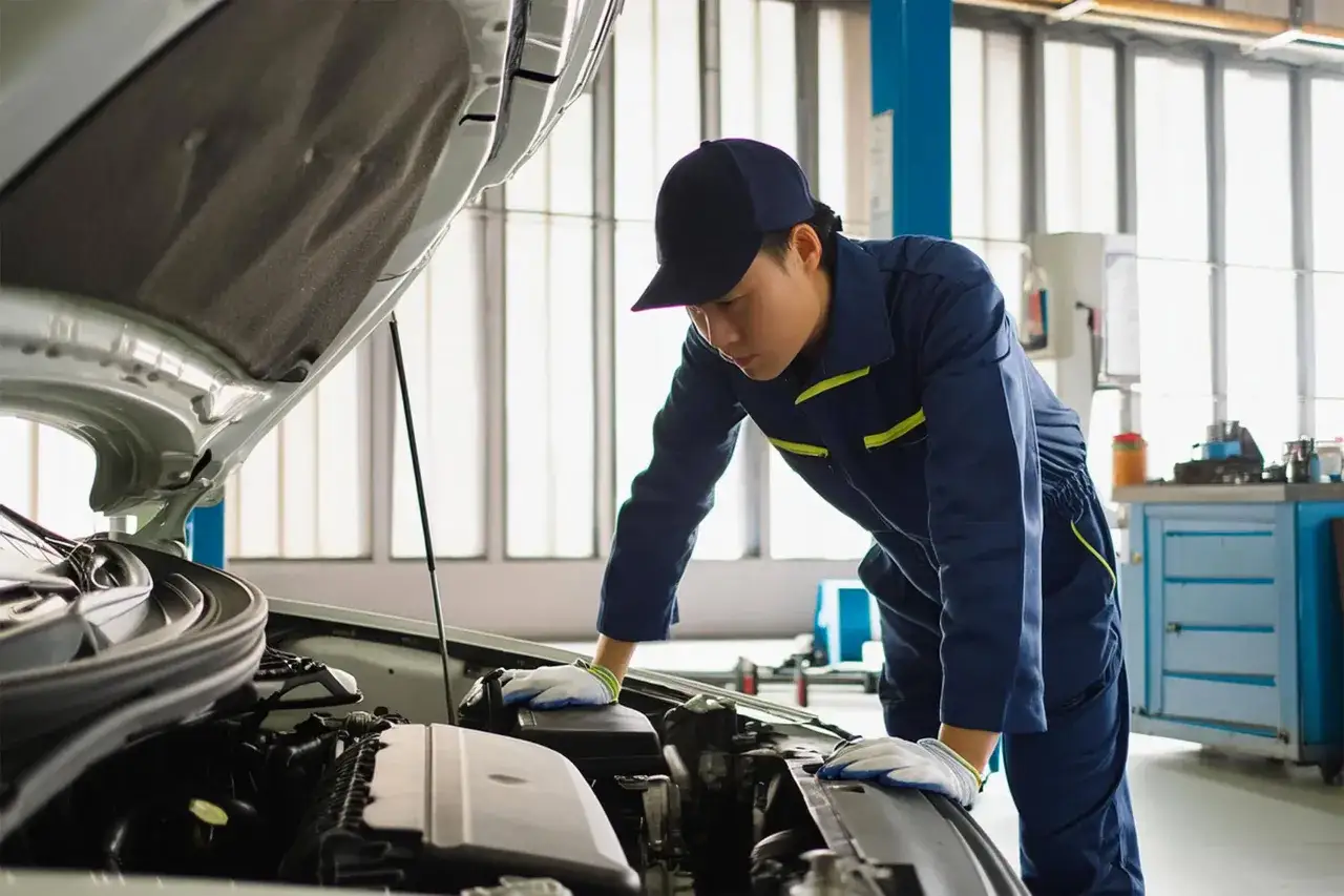 M&eacute;canicien en bleu de travail examinant un moteur de voiture. Il est temps de v&eacute;rifier le **tarif entretien mini** pour votre v&eacute;hicule.